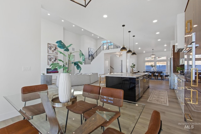 dining room featuring sink, light wood-type flooring, and a high ceiling