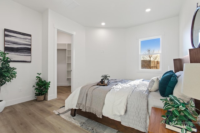 bedroom featuring a walk in closet, a closet, and light wood-type flooring