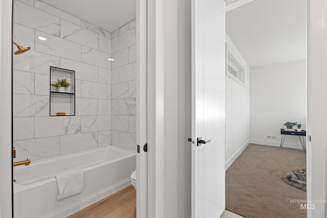 bathroom with toilet and tiled shower / bath combo