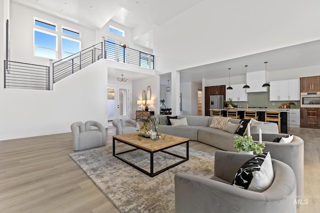 living room featuring a notable chandelier, light hardwood / wood-style flooring, and a high ceiling