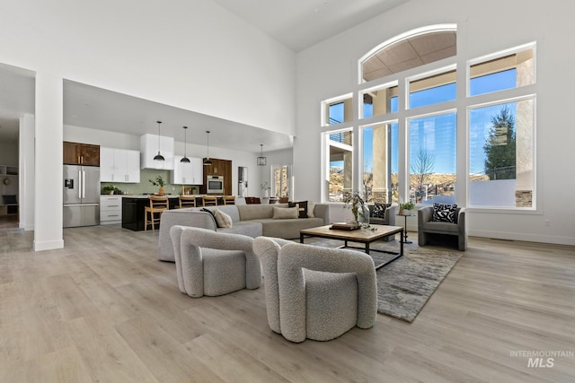 living room with a towering ceiling and light hardwood / wood-style flooring