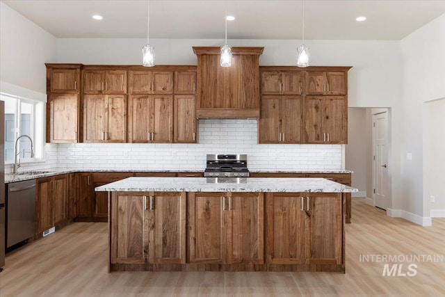 3119 Crescent Moon Rd, Twin Falls, ID 83301 - kitchen featuring stainless steel appliances, light wood finished floors, decorative backsplash, a center island, and light stone counters