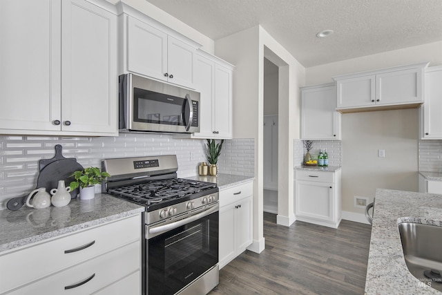 kitchen with white cabinets, dark wood-style floors, light stone countertops, stainless steel appliances, and a textured ceiling