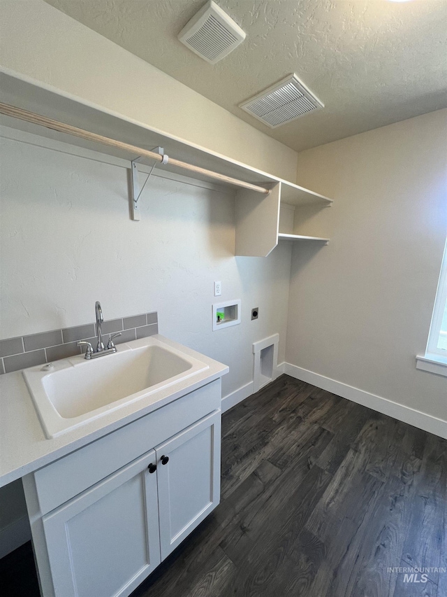 washroom with sink, hookup for a washing machine, a textured ceiling, hookup for an electric dryer, and dark hardwood / wood-style flooring