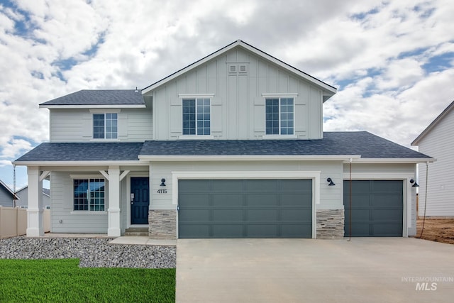 view of front of home featuring a garage, concrete driveway, board and batten siding, and stone siding