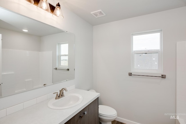 bathroom with toilet, visible vents, and vanity