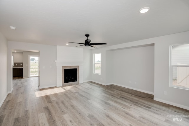 unfurnished living room featuring a large fireplace, baseboards, a ceiling fan, light wood-style floors, and recessed lighting