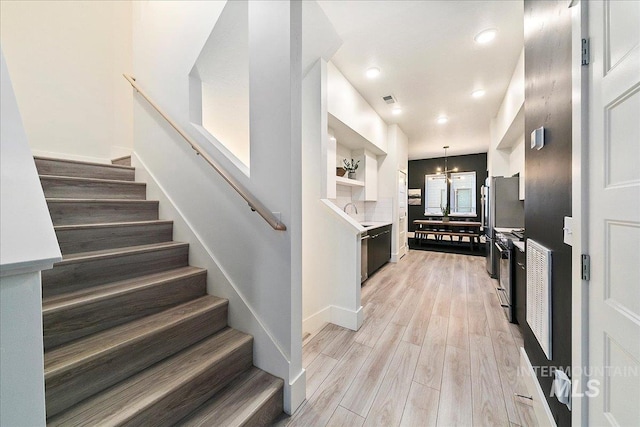 staircase with baseboards, visible vents, wood finished floors, a chandelier, and recessed lighting