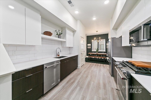 kitchen featuring open shelves, white cabinetry, stainless steel appliances, and a sink