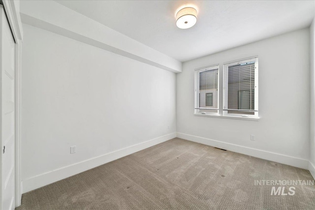 spare room featuring visible vents, light colored carpet, and baseboards