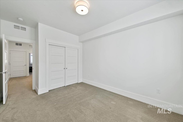 unfurnished bedroom featuring baseboards, a closet, visible vents, and light colored carpet