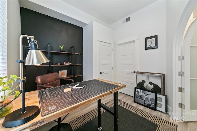 home office featuring arched walkways, visible vents, and wood finished floors