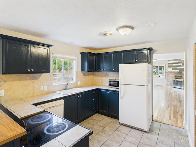 2624 Iowa Ave, Caldwell, ID 83605 - kitchen featuring white appliances, tile countertops, backsplash, and light tile patterned flooring