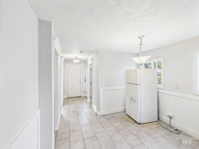 2624 Iowa Ave, Caldwell, ID 83605 - kitchen with freestanding refrigerator, light tile patterned floors, wainscoting, a textured ceiling, and hanging light fixtures