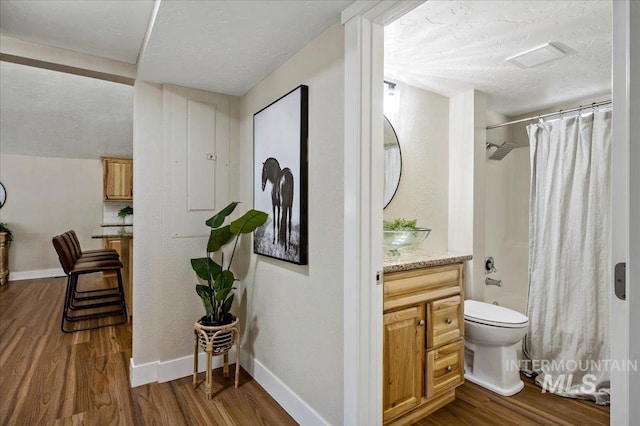 full bathroom with vanity, hardwood / wood-style floors, shower / bath combo with shower curtain, and a textured ceiling