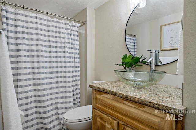 bathroom with a textured ceiling, toilet, and vanity