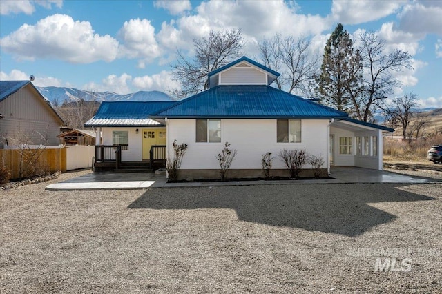 back of house with a mountain view, a carport, and covered porch