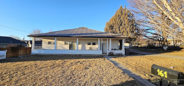 view of front of house featuring a porch, metal roof, and fence