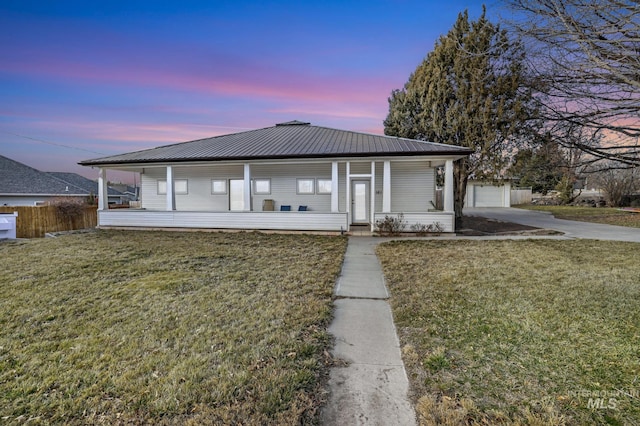 view of front of house with covered porch, metal roof, concrete driveway, and a yard