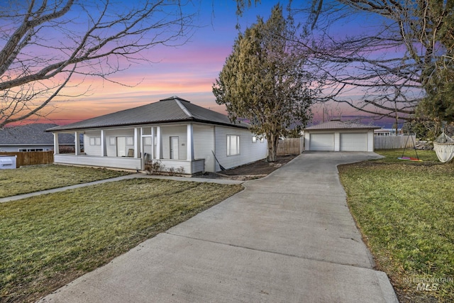 view of front of house with metal roof, a garage, an outdoor structure, fence, and a yard