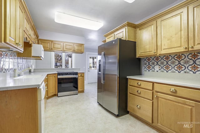 kitchen featuring stainless steel appliances, a sink, light countertops, and decorative backsplash