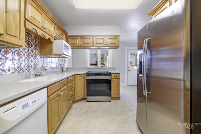 kitchen featuring a peninsula, white appliances, light countertops, and a sink