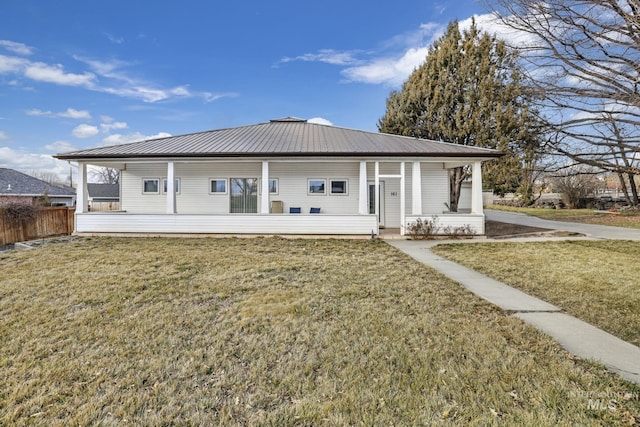 back of property featuring covered porch, fence, metal roof, and a lawn