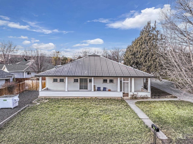 back of house featuring fence, metal roof, and a yard