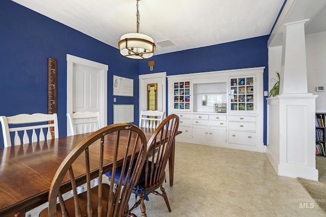 dining space featuring a chandelier and ornate columns