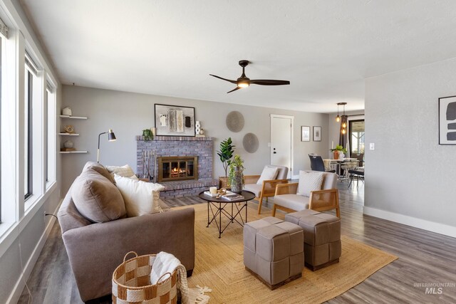 living room featuring light wood-style flooring, ceiling fan, baseboards, and a fireplace