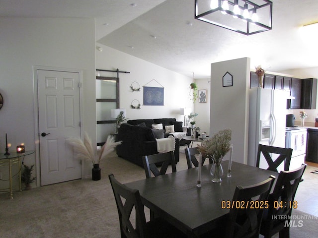 dining room with light colored carpet, vaulted ceiling, and a barn door