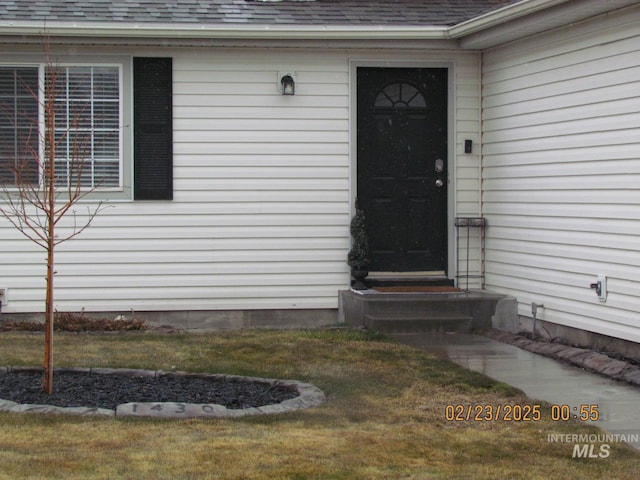 property entrance with a yard and roof with shingles