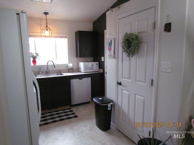 kitchen featuring white appliances, a sink, light countertops, light floors, and pendant lighting