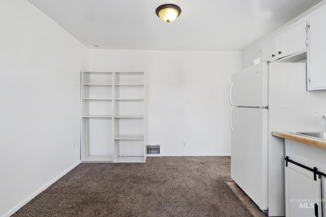 interior space featuring dark colored carpet, visible vents, and baseboards