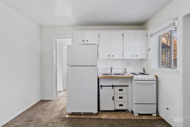 kitchen with white appliances, white cabinets, carpet, light countertops, and a sink