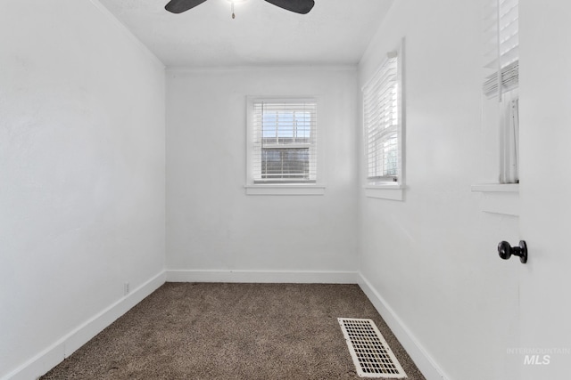 carpeted empty room featuring baseboards, visible vents, and a ceiling fan