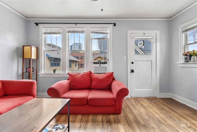 living room featuring cooling unit, a textured ceiling, baseboards, and wood finished floors