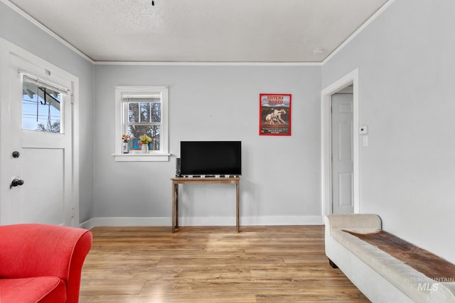 living area featuring crown molding, a textured ceiling, baseboards, and wood finished floors