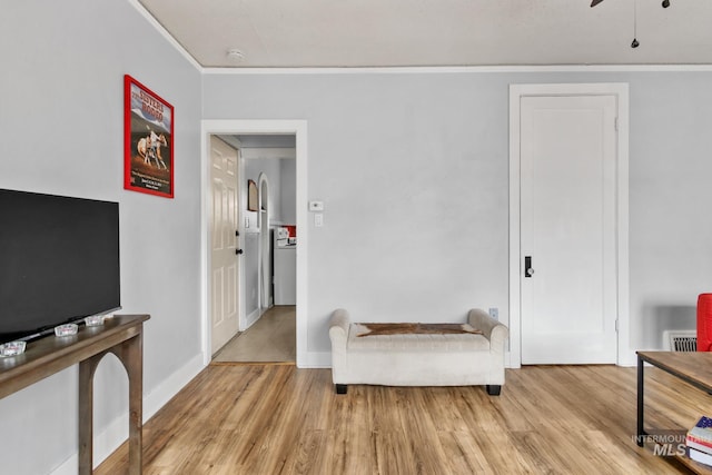 living area with ornamental molding, wood finished floors, and baseboards