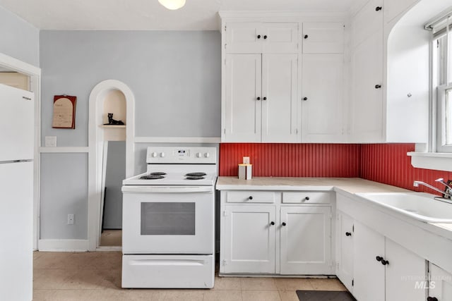 kitchen with light countertops, white cabinetry, a sink, light tile patterned flooring, and white appliances