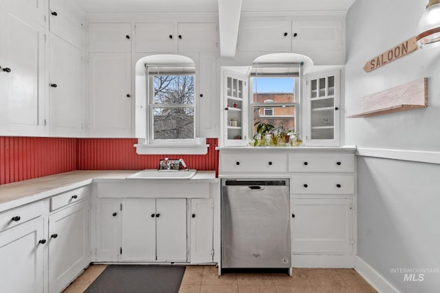 kitchen with light countertops, stainless steel dishwasher, a sink, and white cabinets