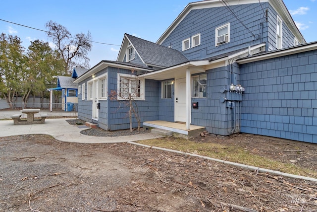 view of front of property with a shingled roof and fence