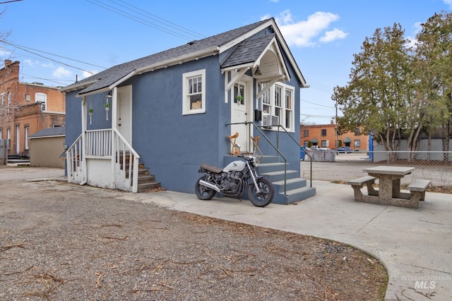 exterior space featuring driveway, a shingled roof, fence, and stucco siding