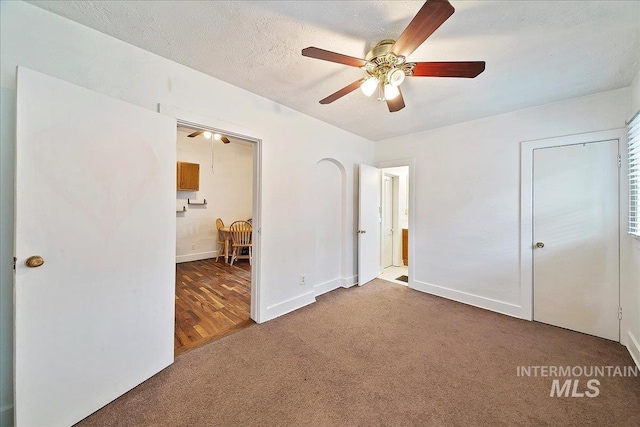 unfurnished bedroom with carpet floors, a textured ceiling, baseboards, and a ceiling fan