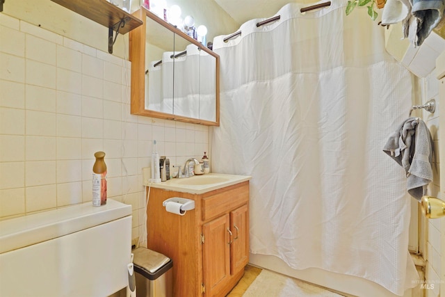 bathroom featuring backsplash, vanity, shower / bathtub combination with curtain, and tile walls