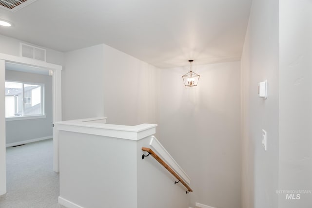 hall with baseboards, an upstairs landing, visible vents, and light colored carpet