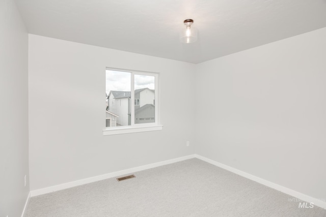 carpeted spare room featuring visible vents and baseboards