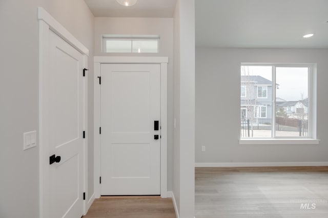 doorway to outside with light wood-type flooring and baseboards