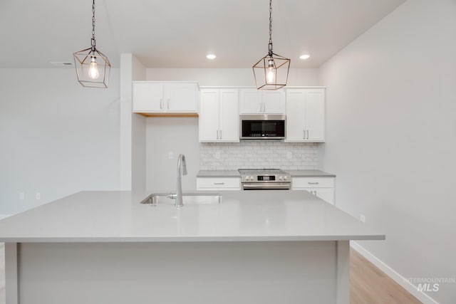 kitchen with pendant lighting, a sink, light countertops, tasteful backsplash, and appliances with stainless steel finishes