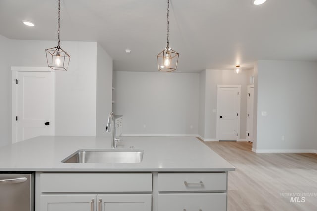 kitchen featuring a sink, open floor plan, light wood-style floors, light countertops, and white cabinets